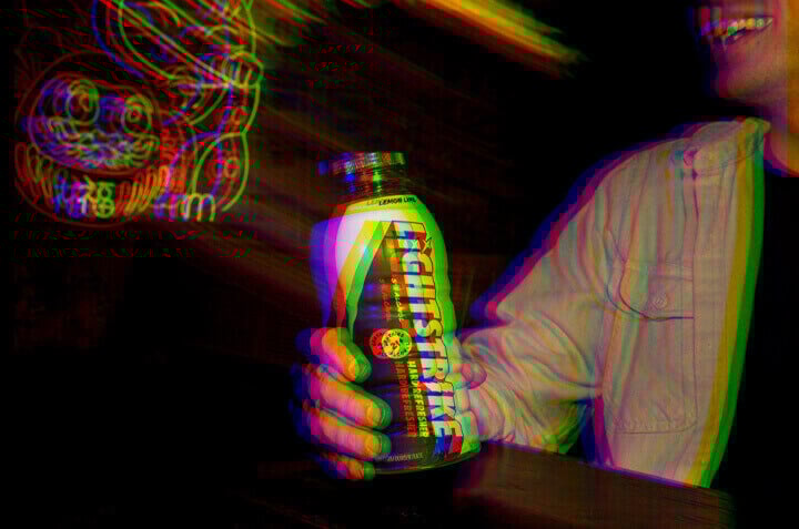Person smiling and holding bottle of Lightstrike Hard Refresher in a bar